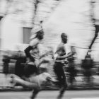 Runners sprint down a street in motion.