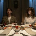 Two adults seated at a candlelit dinner table setting indoors, embodying tradition.