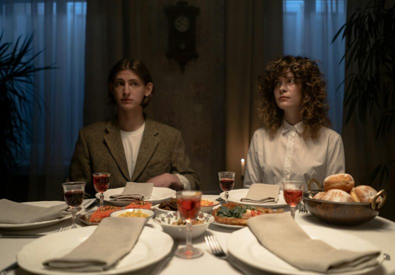 Two adults seated at a candlelit dinner table setting indoors, embodying tradition.