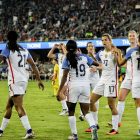 female soccer players at the field near people on bleachers