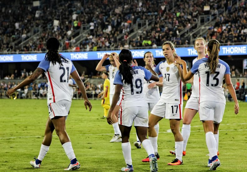 female soccer players at the field near people on bleachers