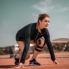 a woman crouches down to pick up a tennis ball